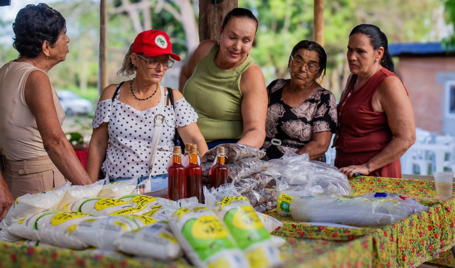 Agricultoras na banca da Feira de Roças e Quintais no Assentamento Roseli Nunes, com mel e produtos Sabor dos Vales