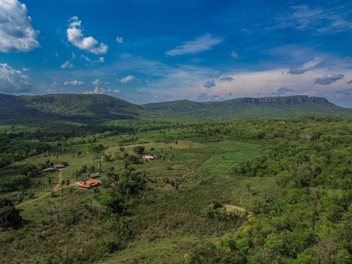 Vista aérea da Terra Indígena Portal do Encantado, com casas da aldeia, roças e a serra ao fundo