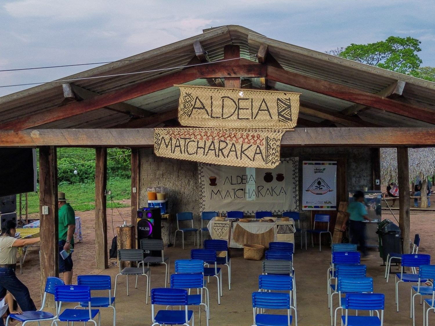 Espaço coberto com faixas Aldeia Matcharaka e cadeiras organizadas para o encontro