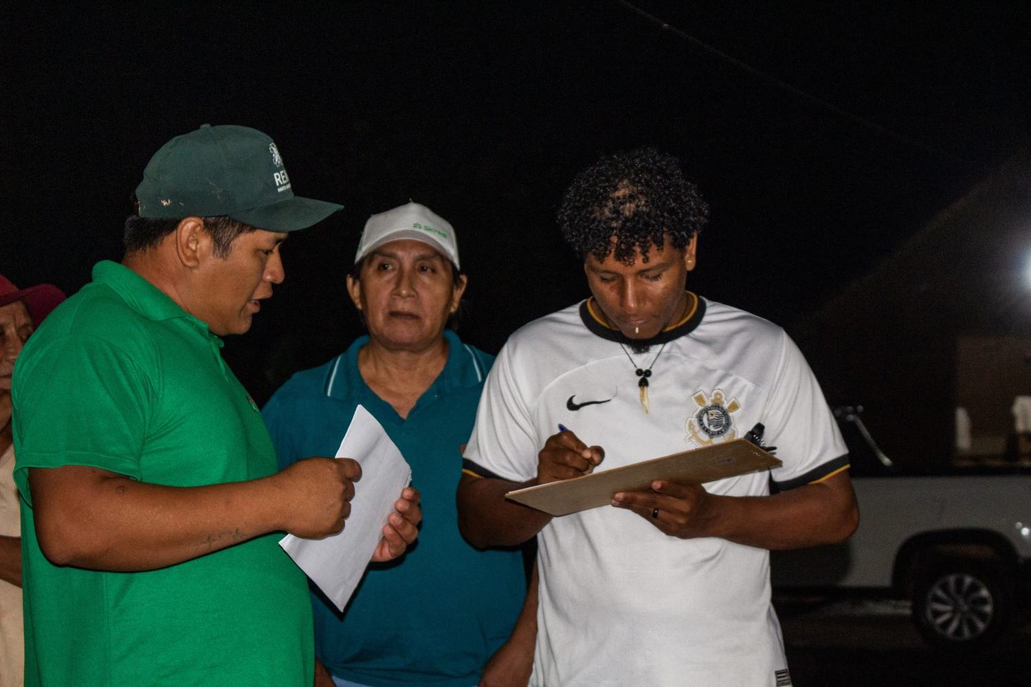 Equipe anota as vendas da feira em prancheta durante a noite