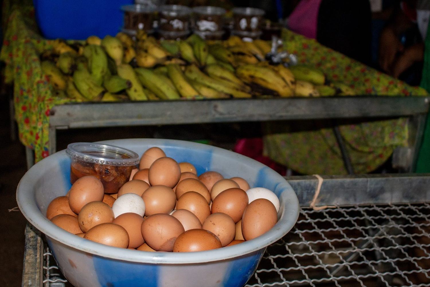 Bacia de ovos caipiras em primeiro plano e bananas expostas na banca ao fundo