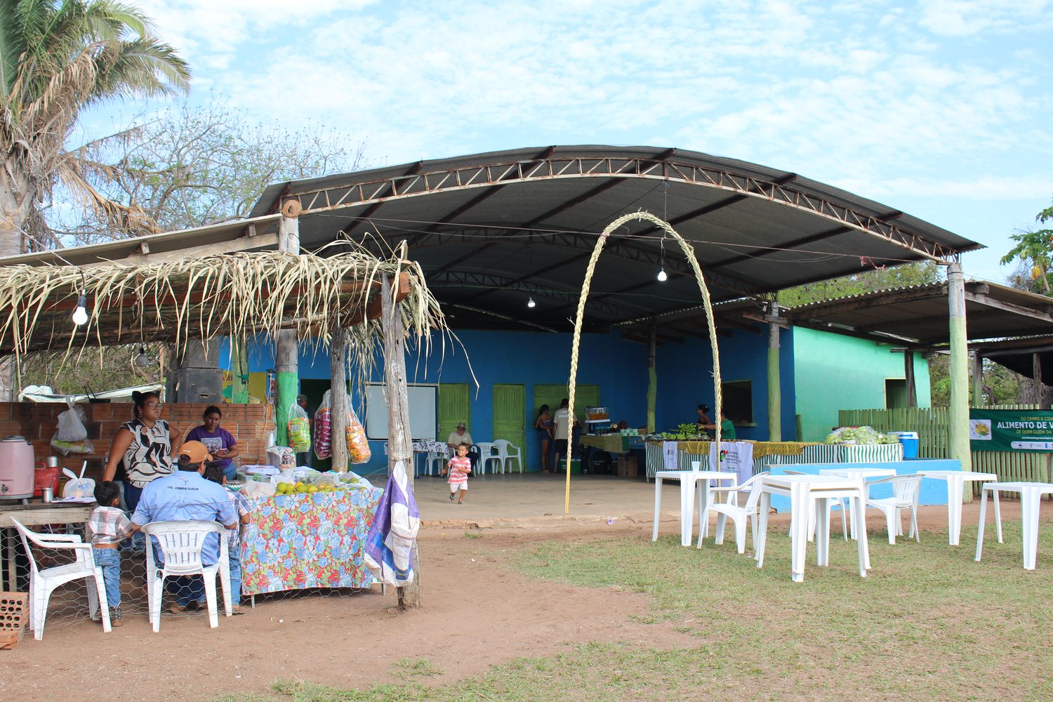 Centro Social da Bocaina com as bancas da feira montadas sob a cobertura e mesas no pátio