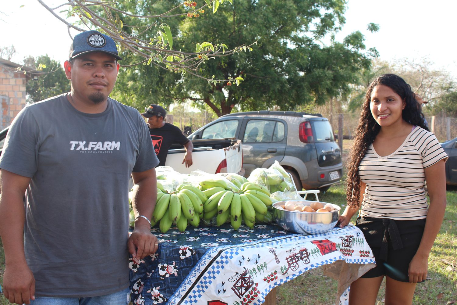 Casal de agricultores ao lado da banca com bananas