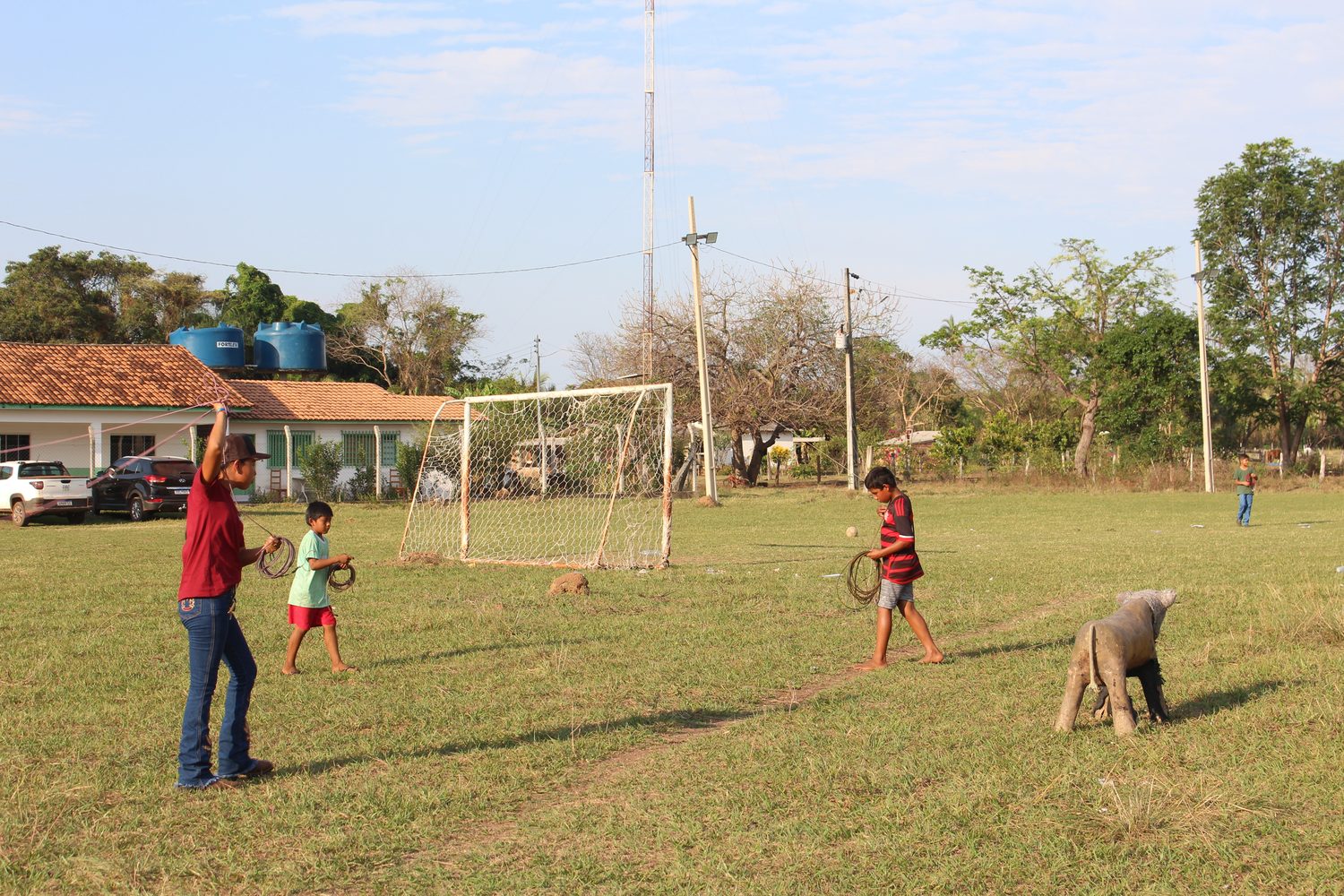 Homem e meninos com laços no campo de futebol da Bocaina, treinando o arremesso num bezerro de mentira