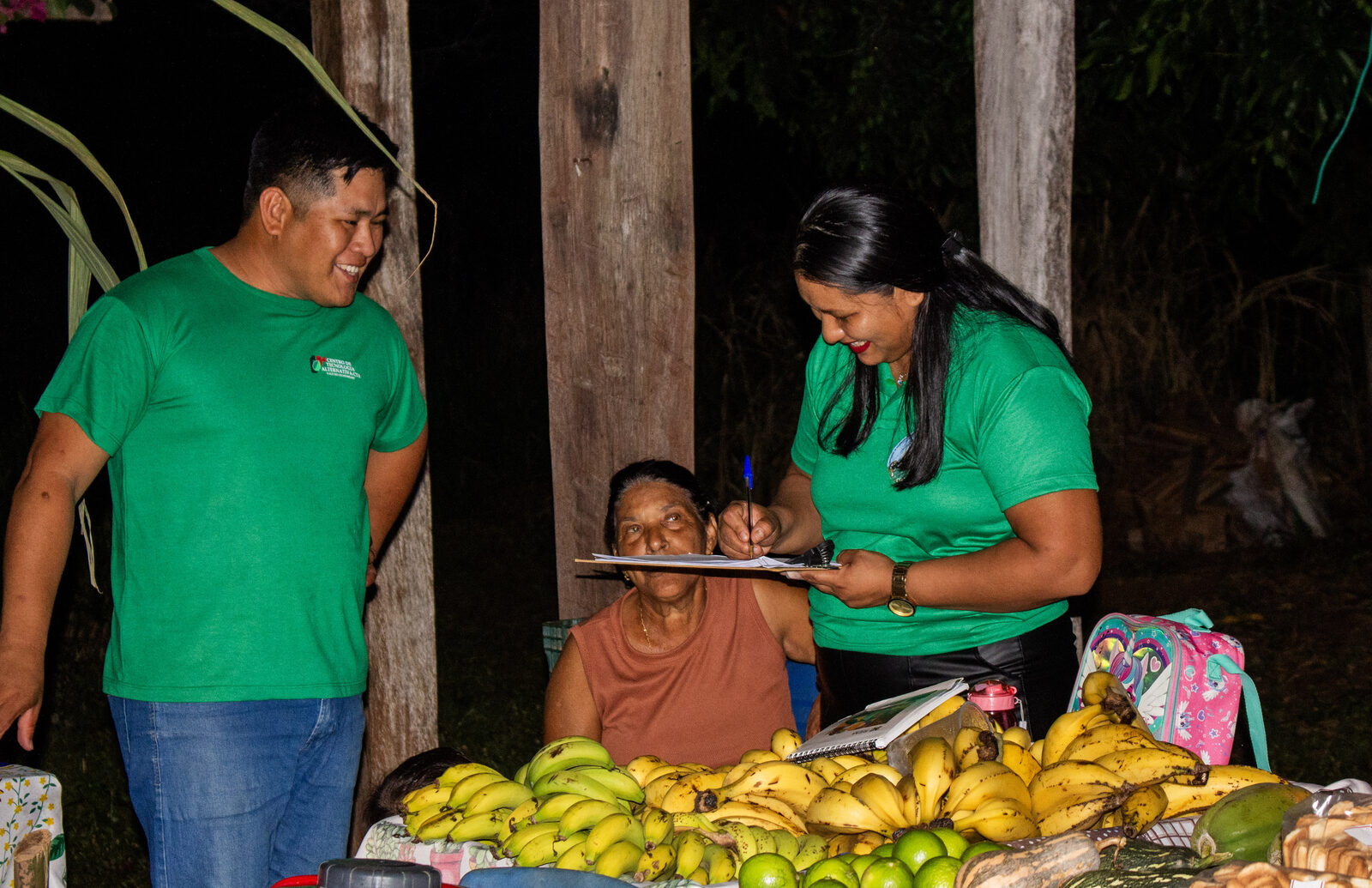 Equipe do CTA registrando as vendas da feira ao lado da banca de bananas