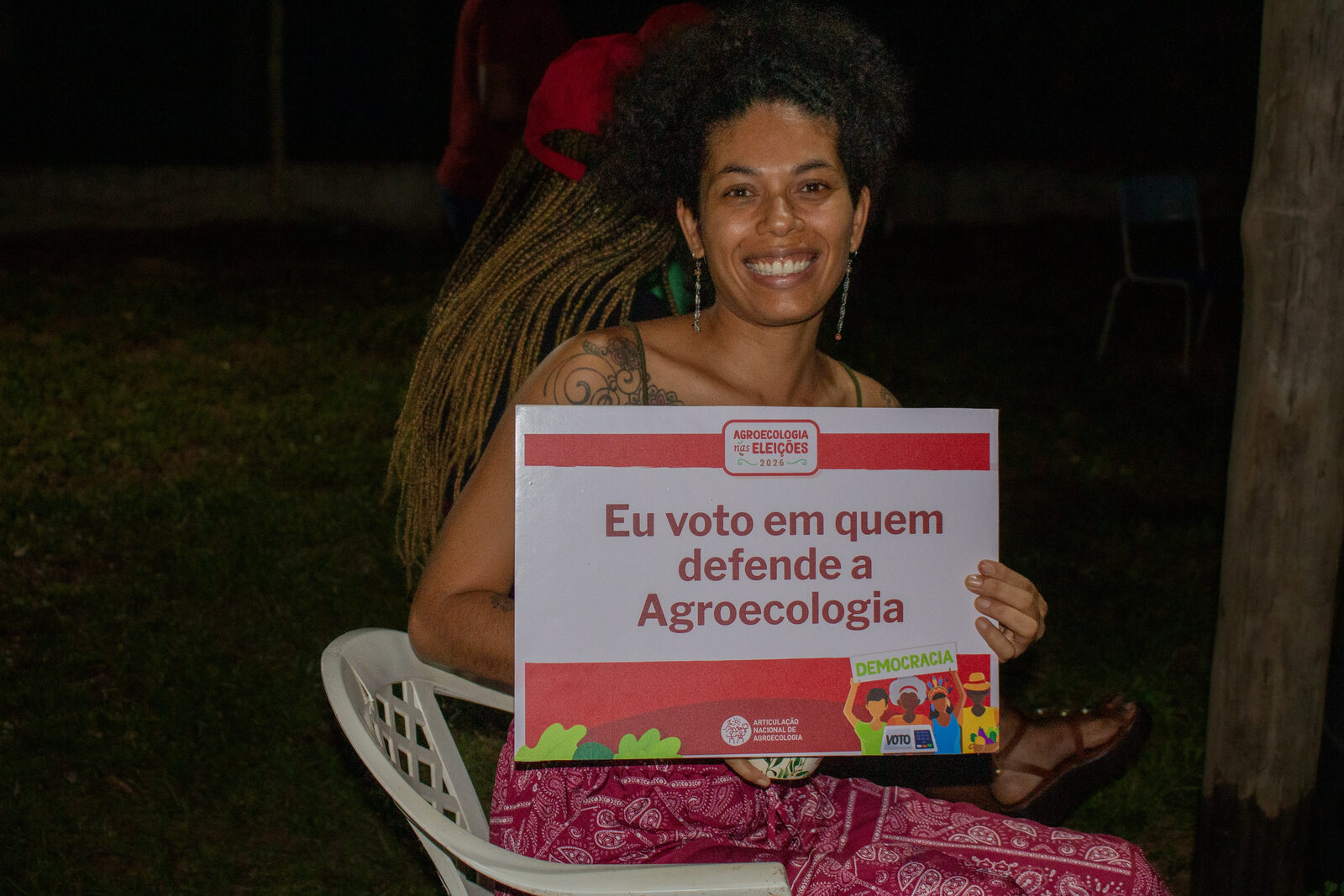 Jovem do território segurando placa da campanha Agroecologia nas Eleições em defesa da agroecologia