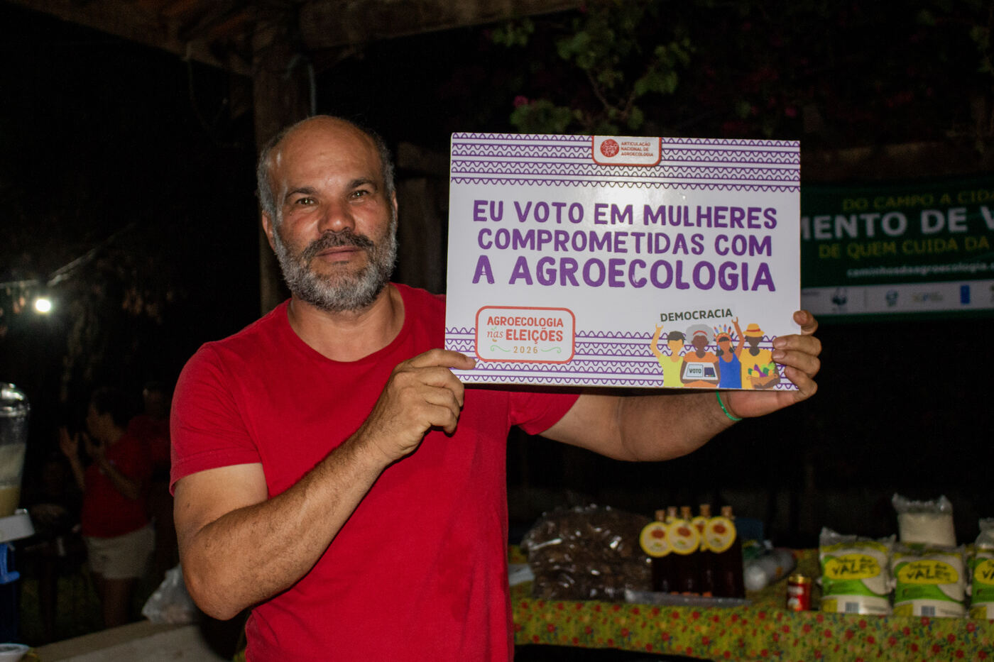 Participante com placa da campanha em defesa das mulheres comprometidas com a agroecologia