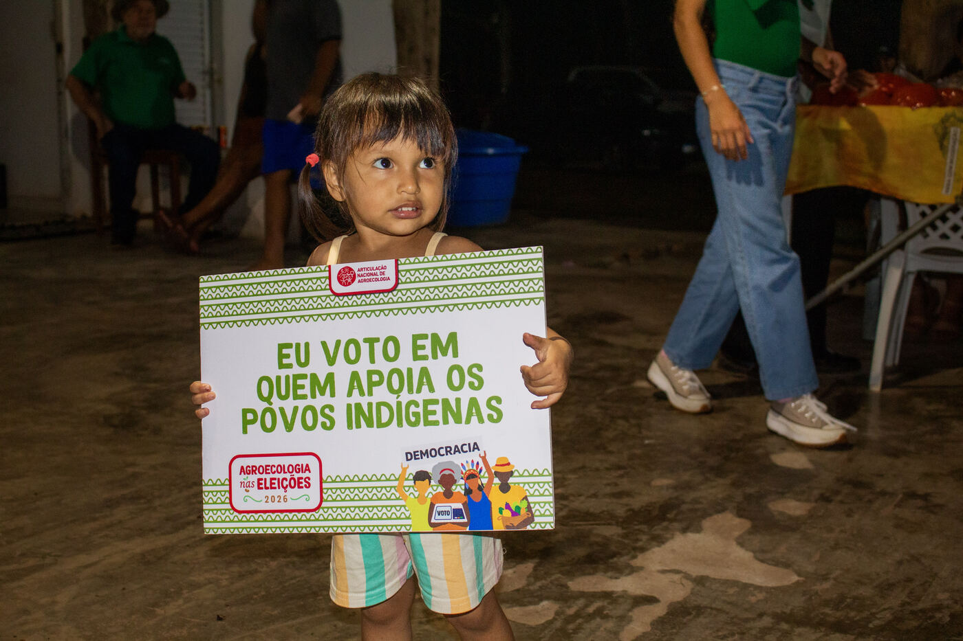Criança segurando placa da campanha em apoio aos povos indígenas