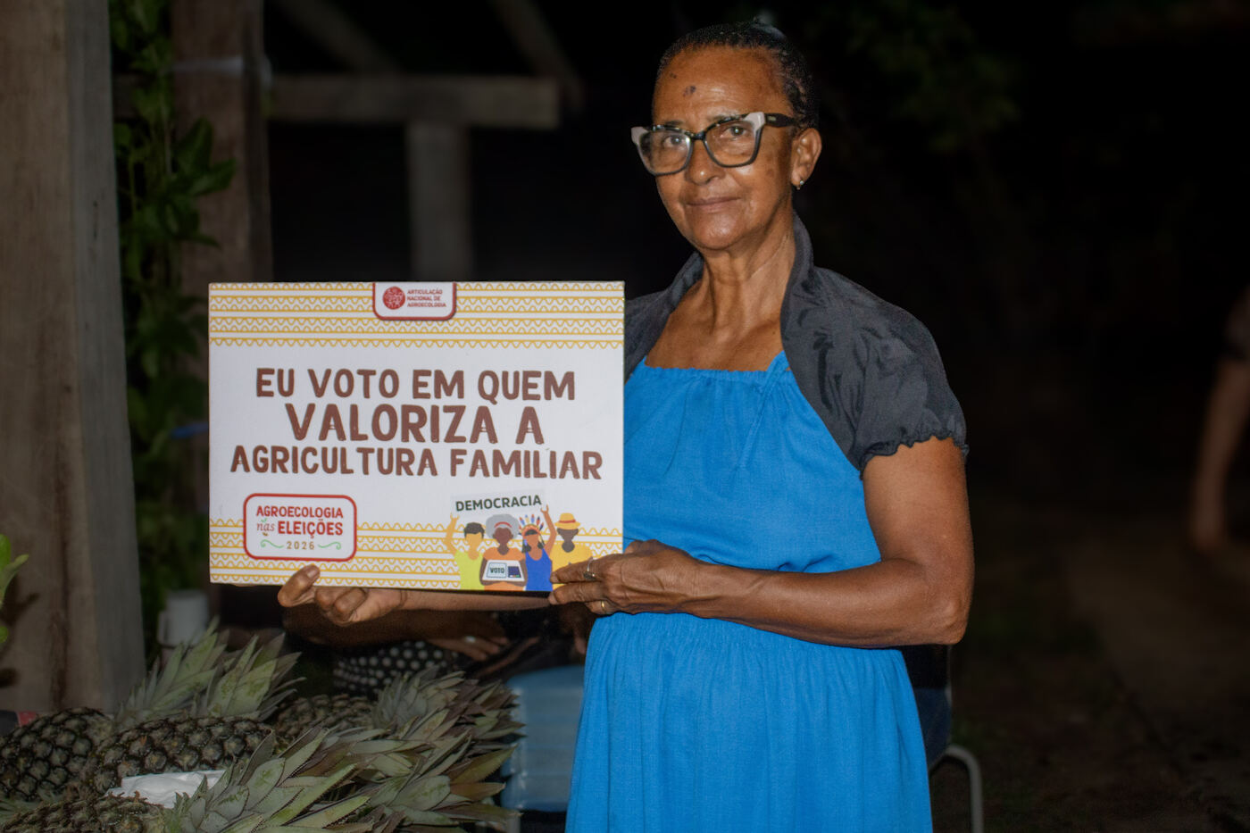 Agricultora com placa da campanha em defesa da agricultura familiar
