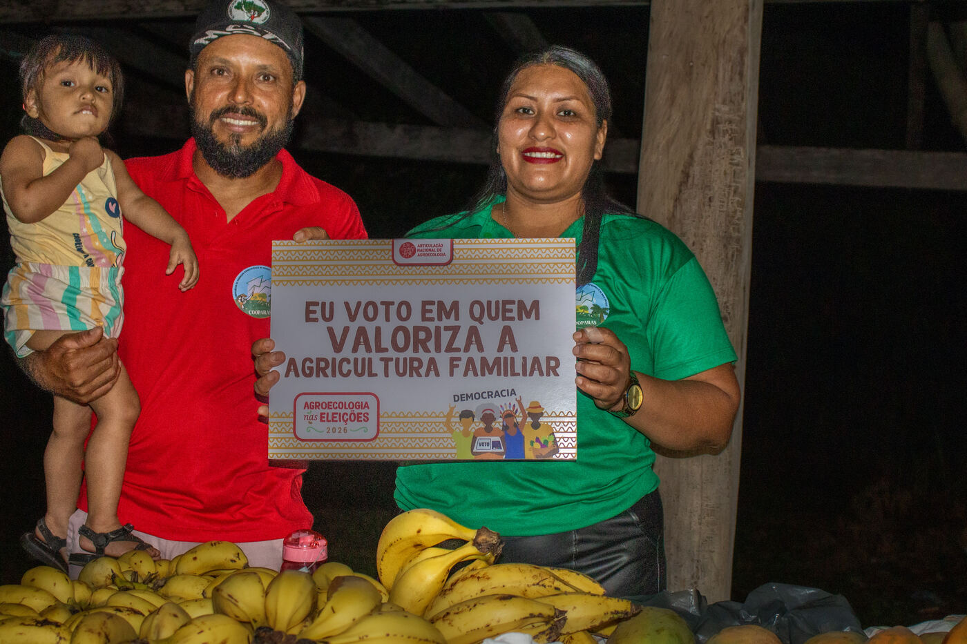 Família com criança no colo segurando placa em defesa da agricultura familiar