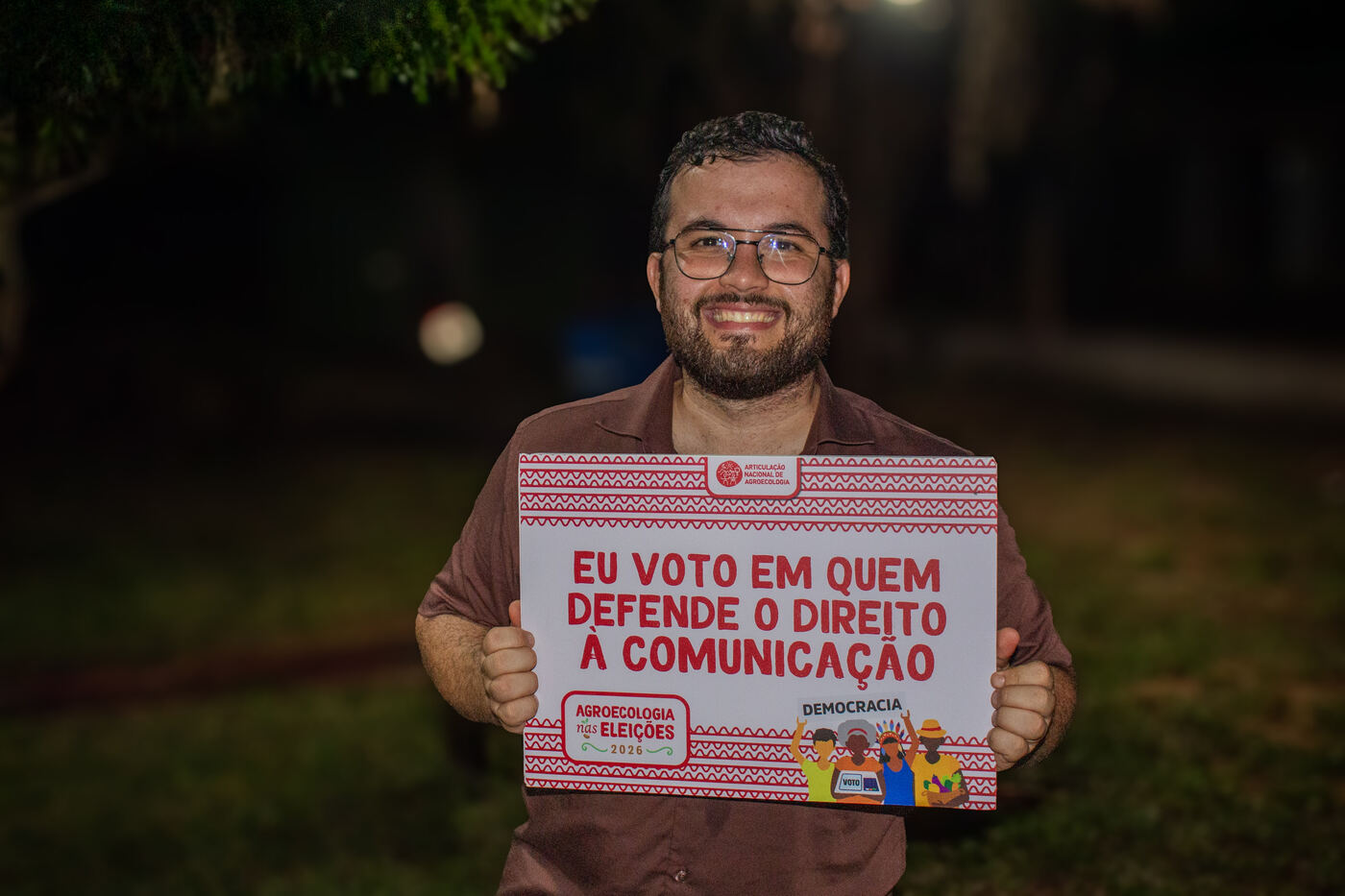 Participante com placa em defesa do direito à comunicação