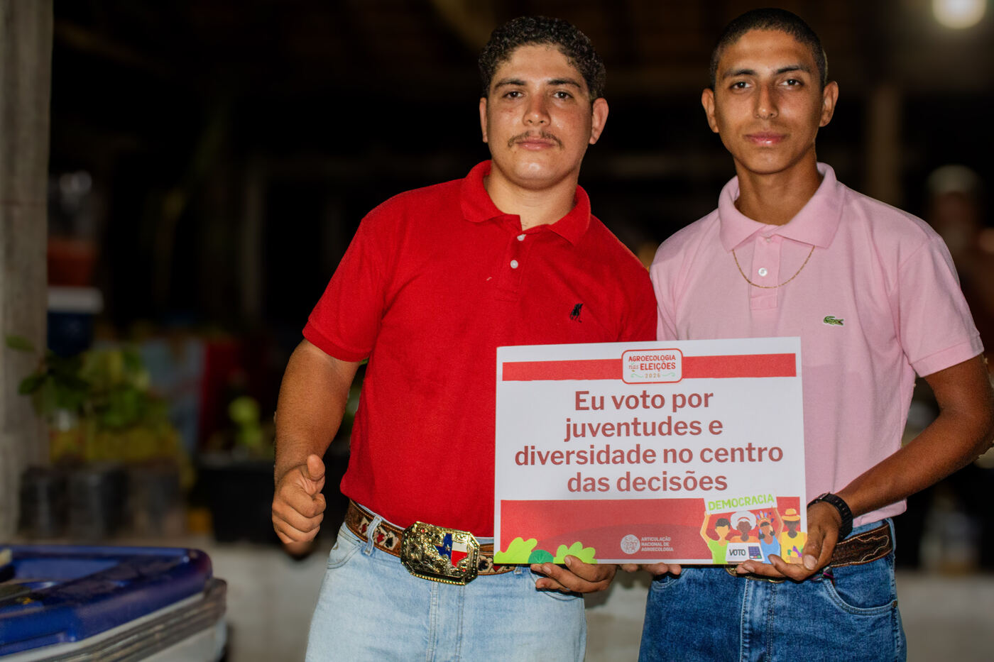 Dois jovens do assentamento com placa por juventudes e diversidade no centro das decisões