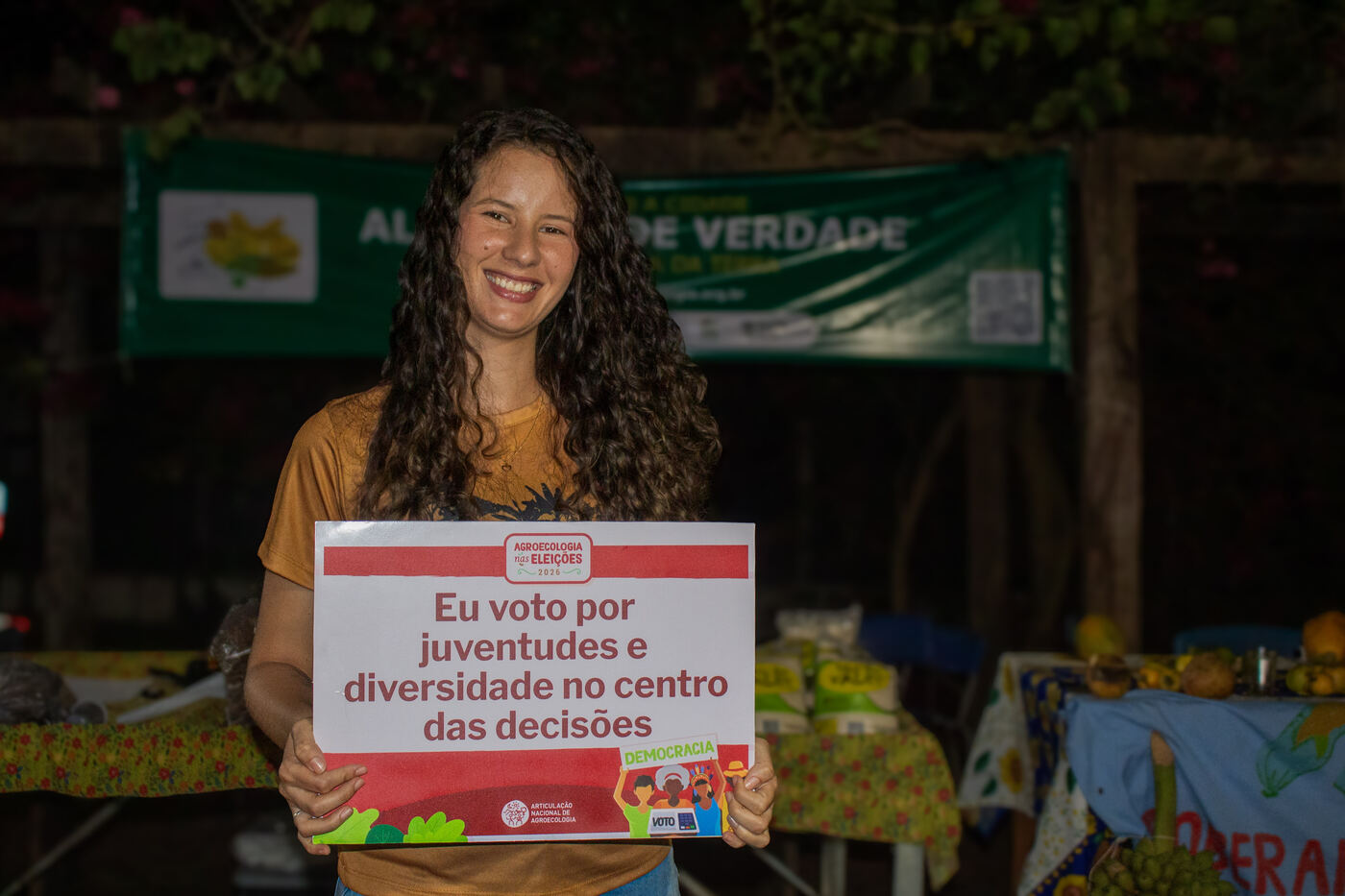 Jovem do território com placa por juventudes e diversidade no centro das decisões
