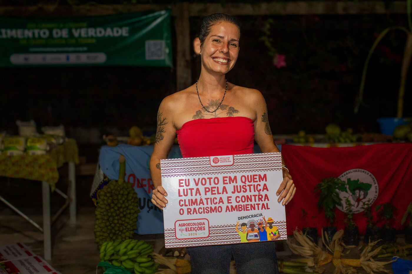 Agricultora com placa por justiça climática e contra o racismo ambiental