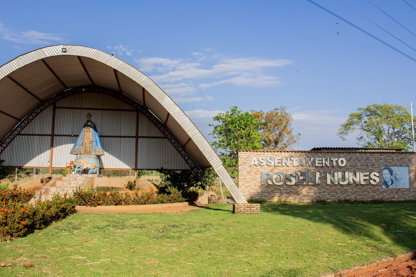 Portal de entrada e igreja do Assentamento Roseli Nunes vistos da estrada