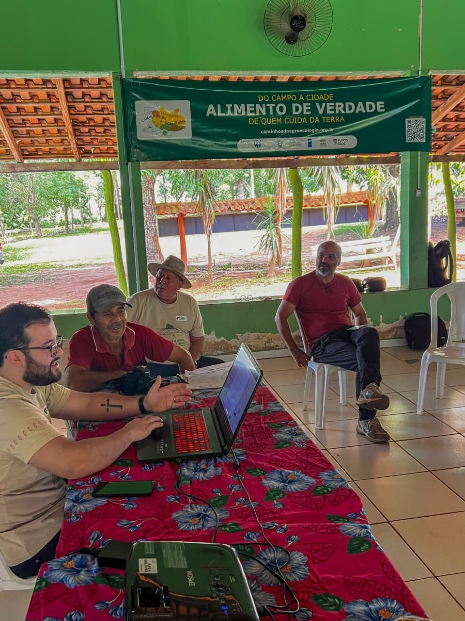 Gabriel Spindulas, do CTA, ao computador, mostrando o cadastro do Balaio ao agricultor Rafael Miguel, sentado ao lado