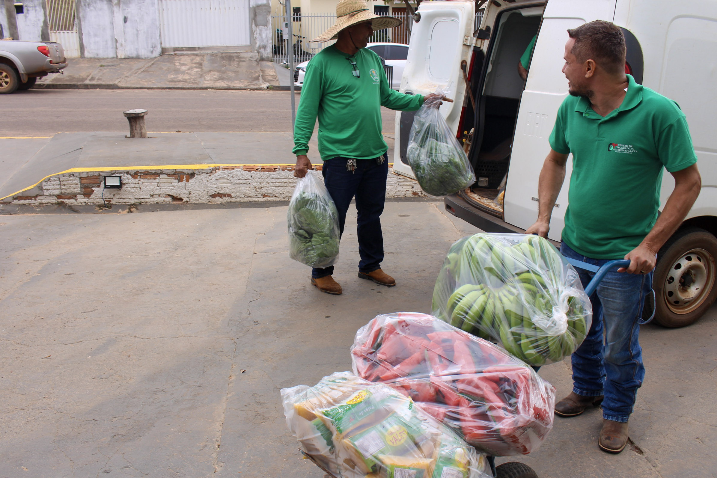 Equipe do CTA descarregando alimentos da van em frente à APAE