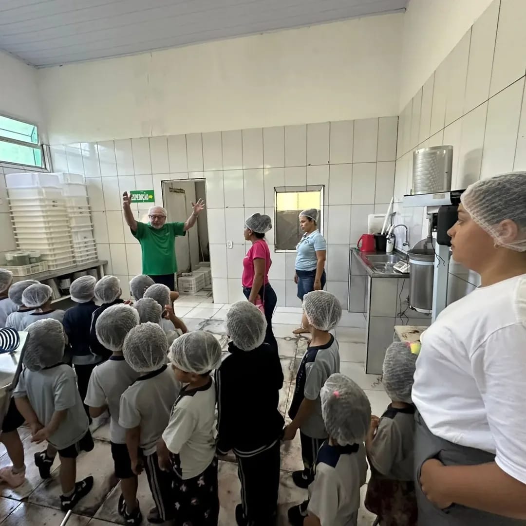 Alunos com toucas de proteção ouvindo explicação de técnico do CTA durante visita à agroindústria